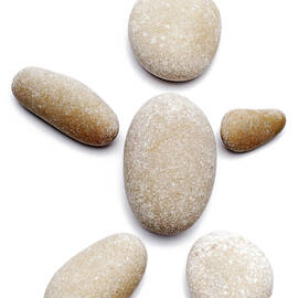 Pebbles arranged in shape of human on white background by Sami Sarkis Photography