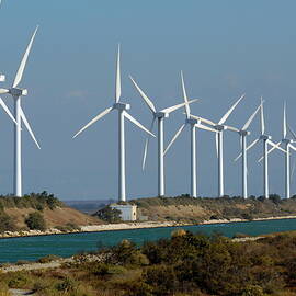 Row of wind turbines along canal by Sami Sarkis Photography
