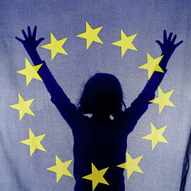 Silhouette of girl with arms raised behind European Union Flag by Sami Sarkis Photography