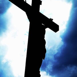 Silhouetted crucifix against a cloudy sky by Sami Sarkis Photography