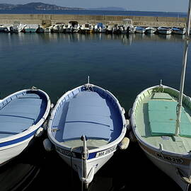Small fishing boats lined up in a near row by Sami Sarkis Photography