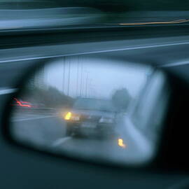 Speeding car on a highway reflected in the rear view mirror of another car by Sami Sarkis Photography
