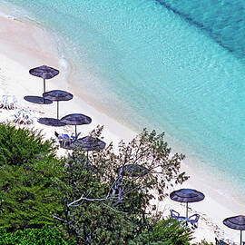 Sun umbrellas dotted along the white sand beach on Amedee Island by Sami Sarkis Photography