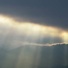 Sunbeams through clouds on mountain range by stormy day by Sami Sarkis Photography