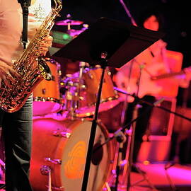 Woman playing saxophone on stage with her band by Sami Sarkis Photography