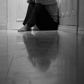 Woman sitting in corridor with head in hands by Sami Sarkis Photography