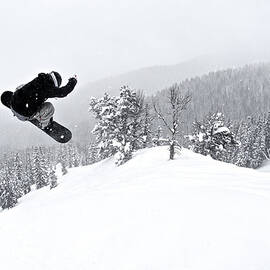 A Man On A Snowboard Flies Through The by Derek Diluzio