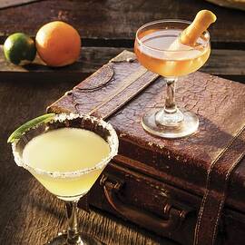 A Margarita Cocktail And A Manhattan Cocktail On An Old Suitcase by Cindy Haigwood