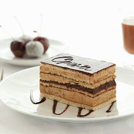 A Slice Of Opera Cake With Cherries And A Glass Of Chocolate Liqueur In The Background by Jane Saunders