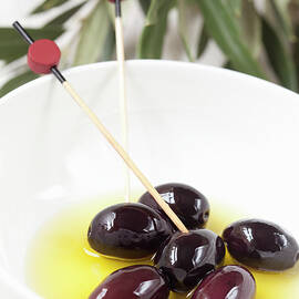 Black Kalamata Olives In Bowls With Wooden Skewers by Hilde Mèche