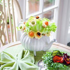 Bouquet Of Salad Leaves And Flowers Made With Cheese, Carrots And Avocado In A Teapot, Cress And Carrots In A Tea Cup On A Green Tablemat by Giulia Verdinelli Photography
