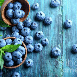 Bowl of fresh blueberries on blue rustic wooden table from above by Jelena Jovanovic