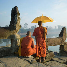 Buddhist Monks Standing Next To Stone by Martin Puddy