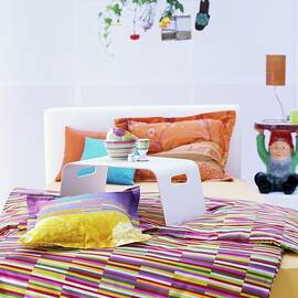 Colourful Textiles In Bedroom With Garden-gnome Bedside Table by Matteo Manduzio