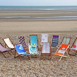 Deckchairs With Various Patterned Fabrics On A Beach With A View Of The Sea by Winfried Heinze