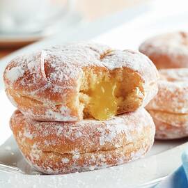 Lemon Jelly Filled Powdered Doughnuts On A White Dish; One Bitten With Jelly Oozing Out by Harrison, Michael S.