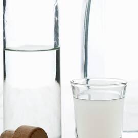 Opalescent Ouzo After Dilution With Water, With An Ouzo Bottle And A Carafe Of Water by Shawn Hempel