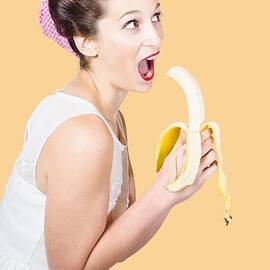 Pin-up woman eating fruit on studio background by Jorgo Photography