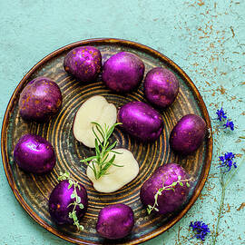 Purple Potatoes With Thyme And Rosemary On A Blue Old Table by Gorobina