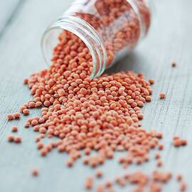 Red Lentils Falling Out Of A Jar by Rafael Pranschke