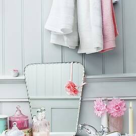 Retro-style Hairdryer On Washstand Next To Various Bottles And Mirror Leaning On Wooden Wall by Biglife