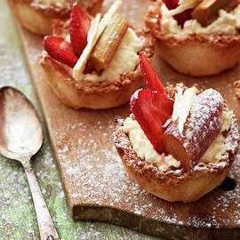 Rhubarb, Strawberry And Coconut Tartlets On A Wooden Board by Hannah Kompanik