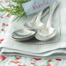 Silver Spoons On Napkin With Name Tag And Sprig Of Rosemary by Martina Schindler