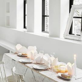 Table Set With Lace Tablecloth And Take-away Cartons Used As Tealight Holders In Loft Apartment by James Stokes