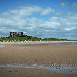 Bamburgh Castle on the horizon above Bamburgh beach by Seeables Visual Arts
