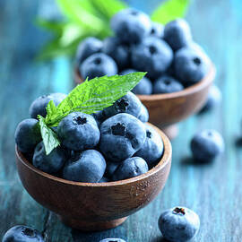 Bowl of fresh blueberries on blue rustic wooden table closeup. by Jelena Jovanovic