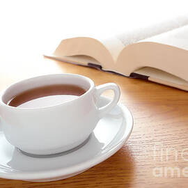 Cup of Coffee and Big Book Leisure on a Wood Table by Olivier Le Queinec