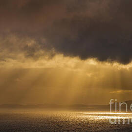 Evening light shining through dark stormy clouds onto the sea, Scotland by Neale And Judith Clark
