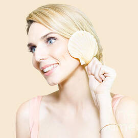 Gorgeous blonde listening for the ocean in a shell by Jorgo Photography