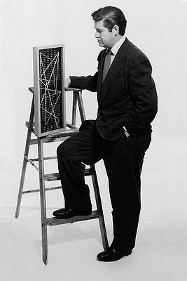 Wall Art featuring the photograph A Portrait Of Paul Mccobb Leaning On A Ladder by Herbert Matter