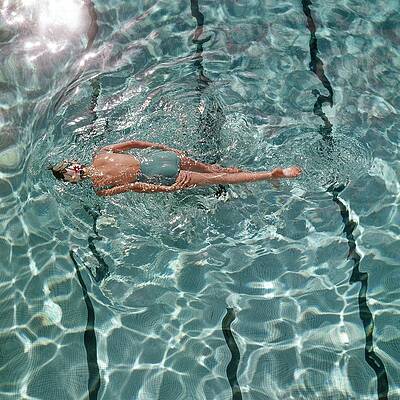 Woman Floating in Sunlit Pool Wall Art