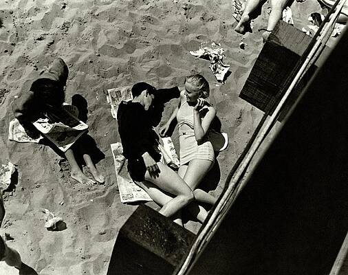 Wall Art featuring the photograph A Young Couple Lying On A Beach by Lusha Nelson