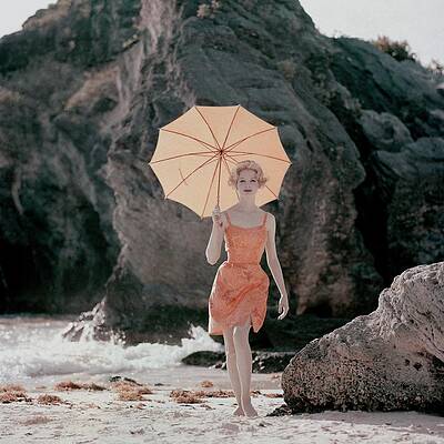 Orange Wall Art featuring the photograph Model Wearing An Orange Bathing Suit Holding by Jerry Schatzberg