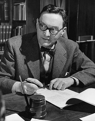 Man Wearing Glasses Writing at Desk Photograph