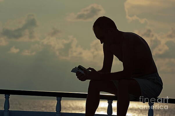Transportation Wall Art featuring the photograph Silhouetted Man Reading A Book On The Boat Deck by Sami Sarkis Photography