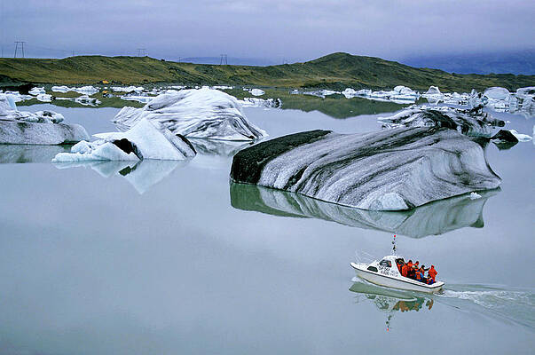 Transportation Wall Art featuring the photograph Tourist Boat Navigating Through Floating Icebergs In The Waters Of Jokulsarlon by Sami Sarkis Photography