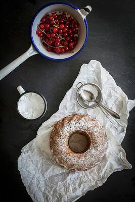 A Bundt Cake Dusted With Icing Sugar On A Piece Of White Paper With Redcurrants In A Vintage Sieve On A Grey Slate Surface Print
