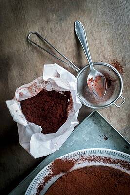 Chocolate Cake On A Metal Tray With Utensils For Sprinkling Cocoa Powder On A Wooden Table Print