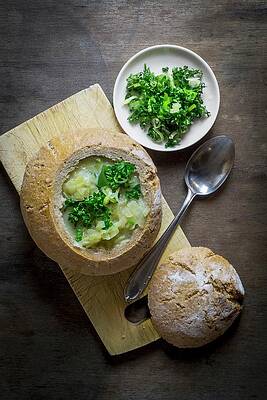 Potato Soup Served In Hollowed Out Bread Garnished With Fresh Herbs Print