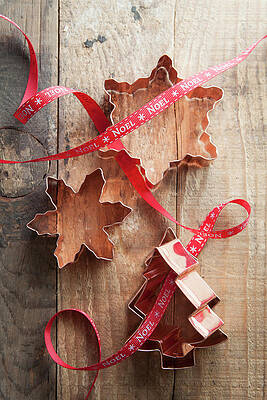 Snowflake And Tree Shape Copper Cookie Cutters On A Rustic Wooden Table With Red Noel Ribbon Print