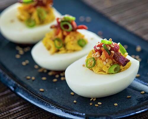 Three Deviled Egg Halves With Green Onions And Bacon Sitting On A Blue Asian-style Plate Print