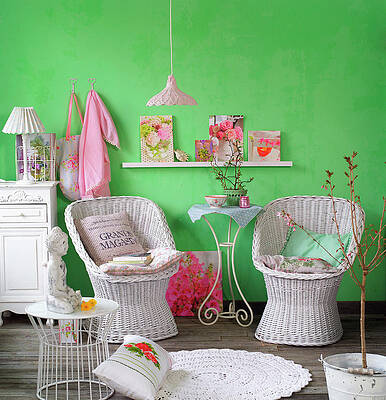 White-painted Wicker Easy Chairs Against Green Wall With Pretty Accessories Print