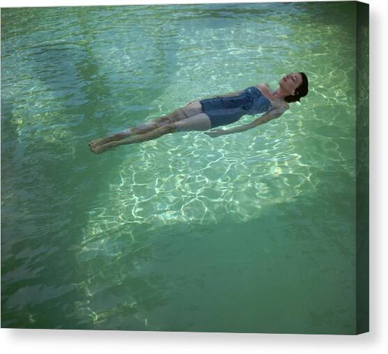 A Model Floating In A Swimming Pool Canvas Art Print by John Rawlings