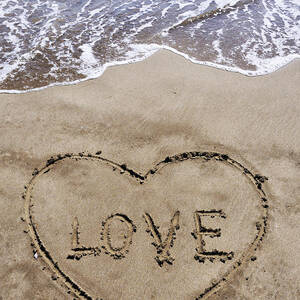 Heartshape drawn in sand on beach with Love word inside by Sami Sarkis Photography