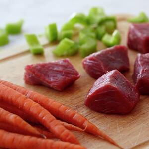 Chunks Of Raw Beef, Raw Carrots And Chopped Celery On A Wooden Cutting Board by Edward Thomas