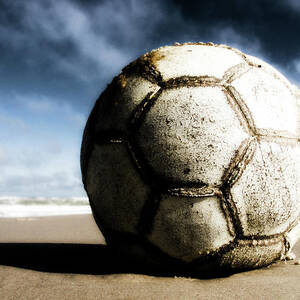 Worn And Old Soccer Ball On Sand by Vithib